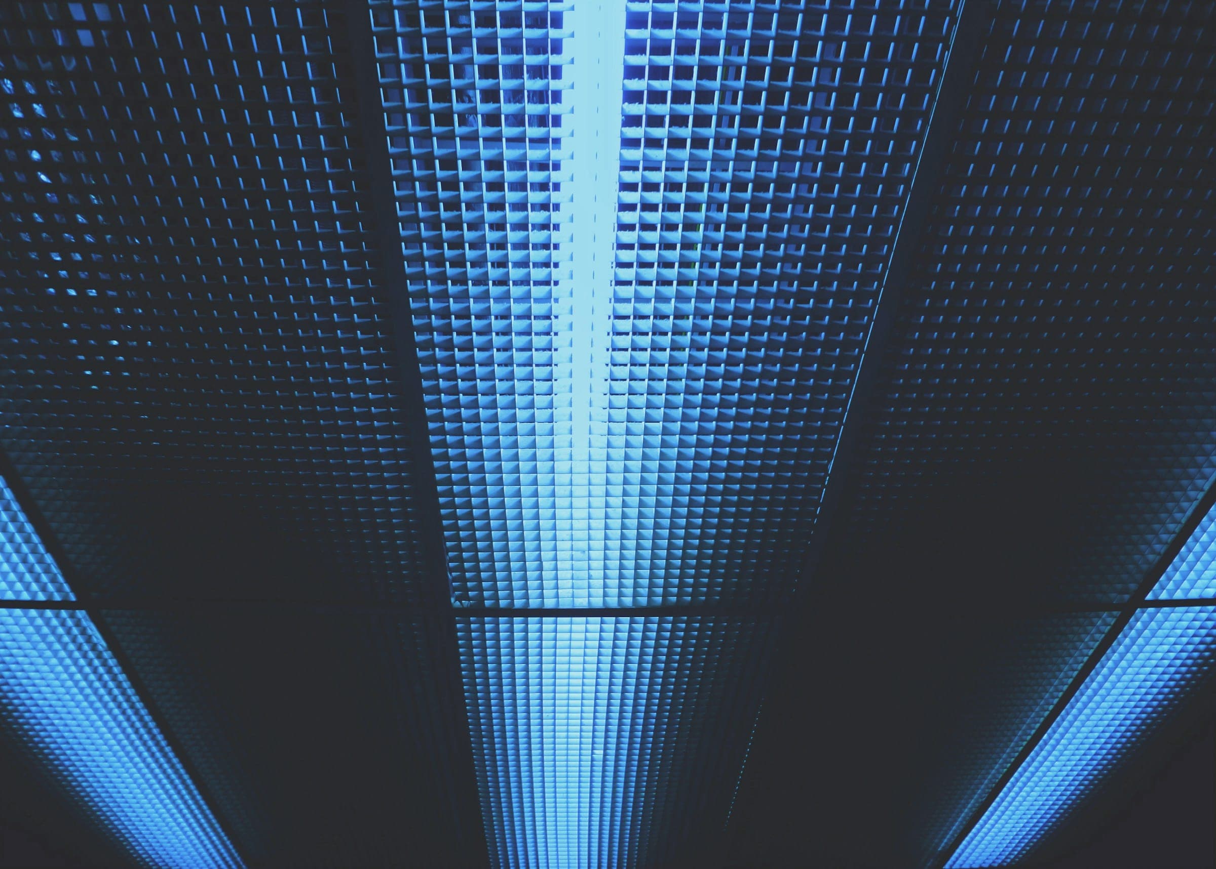 Looking up into a tunnel of blue light panels converging to a vanishing point.